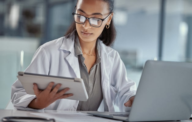 Physician reviews a tablet at a desk