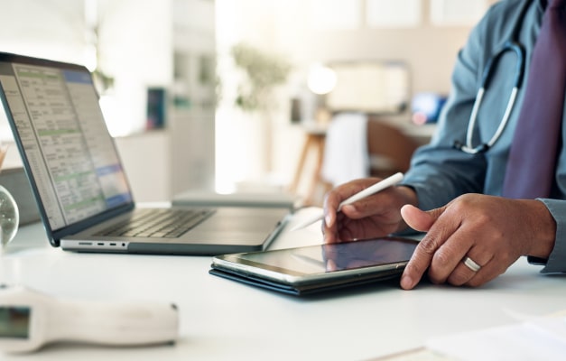 Medical professional holds a tablet at a desk