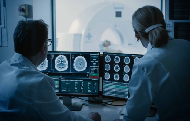 Two medical professionals review brain scans