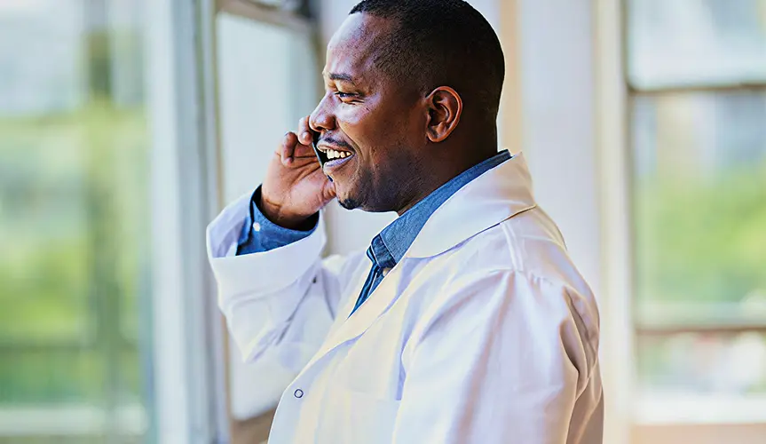 A man in a white coat talking on a mobile phone