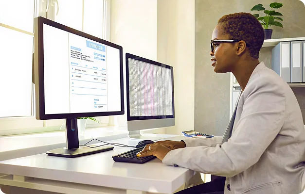 Medical professional reviewing two computer screens at a desk