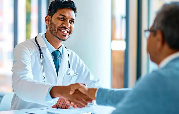 A smiling doctor shakes hands with a patient