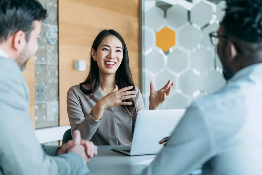Group of three professionals talking at a table in an office setting