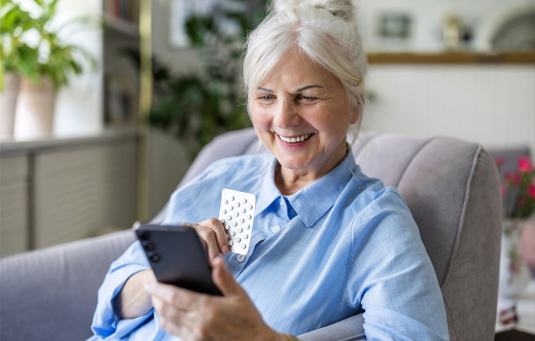 Elderly person smiling while using a mobile phone in a home setting