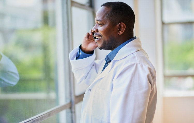 Physician on phone smiling while looking outside a window