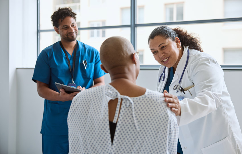 Physician and nurse smiling while speaking with a patient