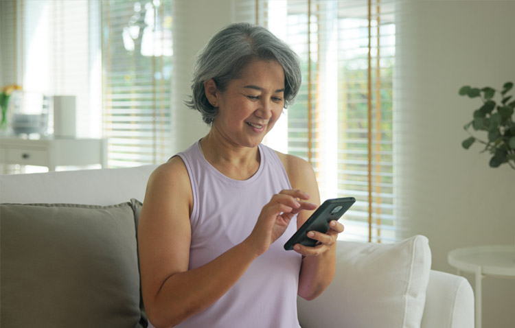 Patient in home setting smiling while using a mobile phone