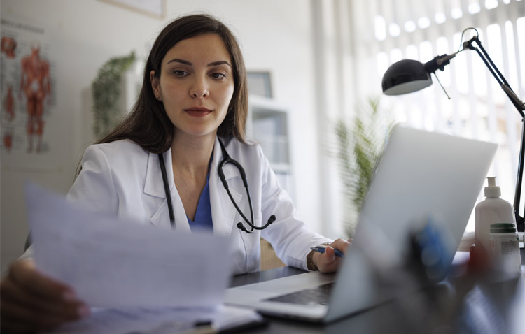 Physician reviews paperwork at desk in medical office