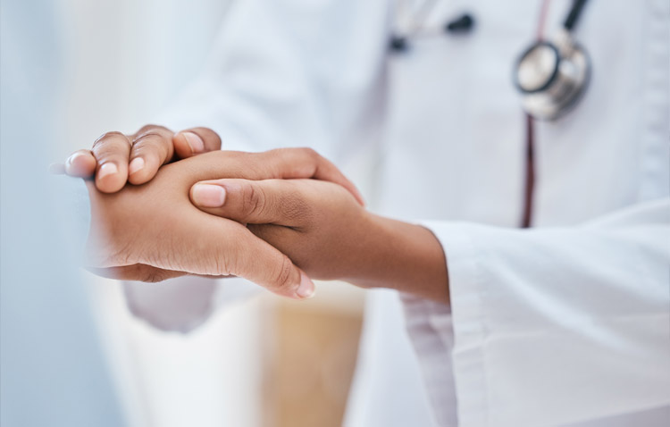 Close up of patient and physician holding hands