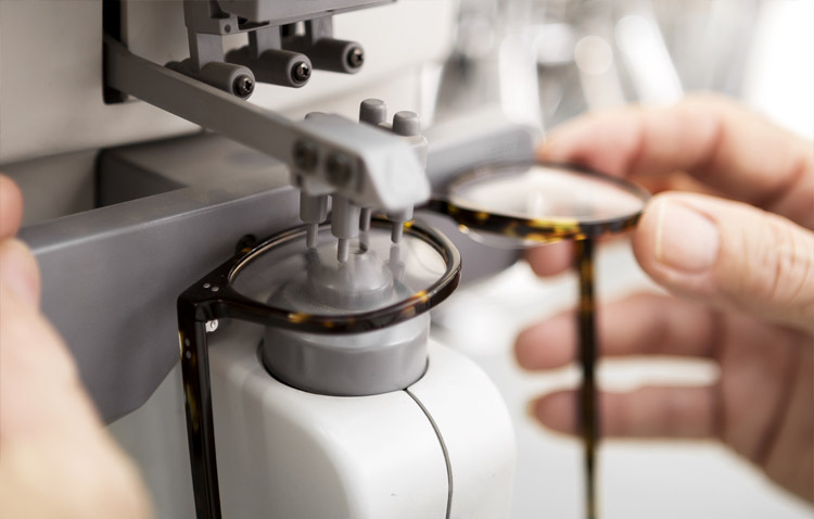 Close up of hands holding eyeglasses in a machine