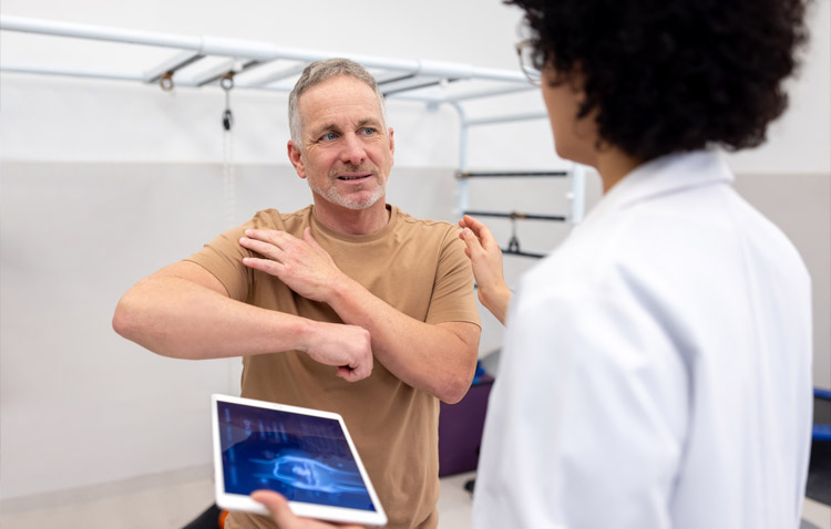 Physician watches patient emphasize his shoulder