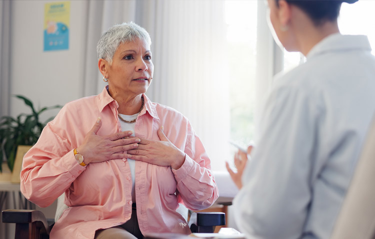 Patient holding her chest while speaking to a medical professional