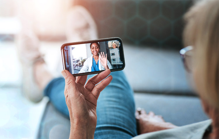 Close up of person looking at a mobile phone with a physician on screen