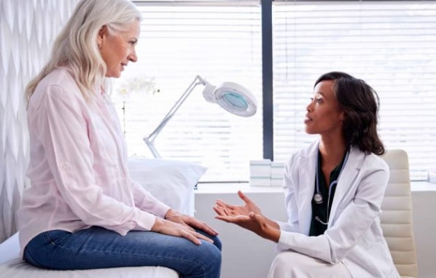 Medical professional speaking with a patient in an exam room