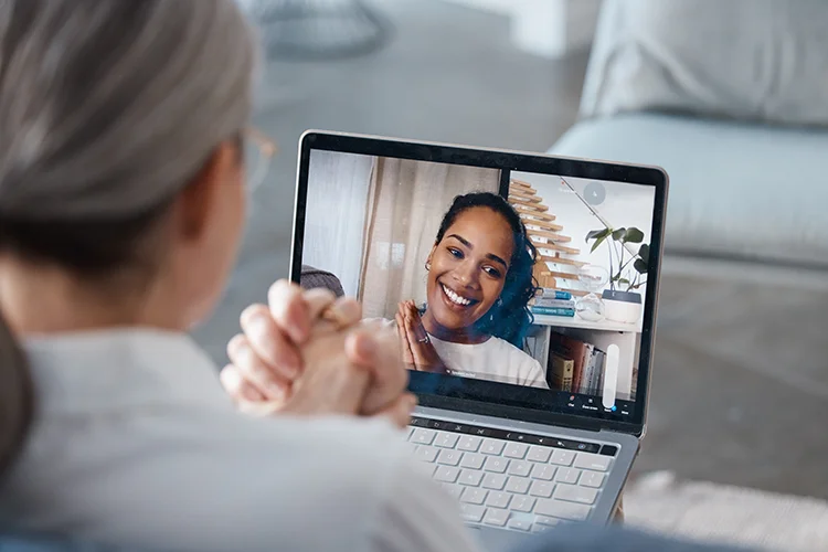 Smiling woman talking with her healthcare provider during a virtual appointment on a laptop