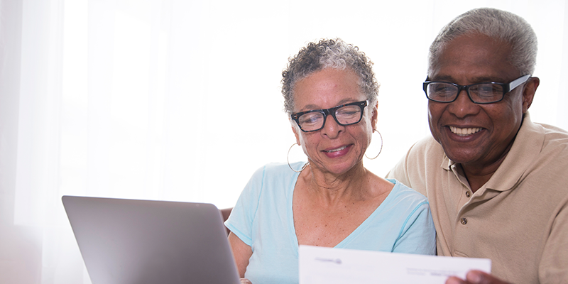Elderly couple looking at medical paperwork in front of a computer